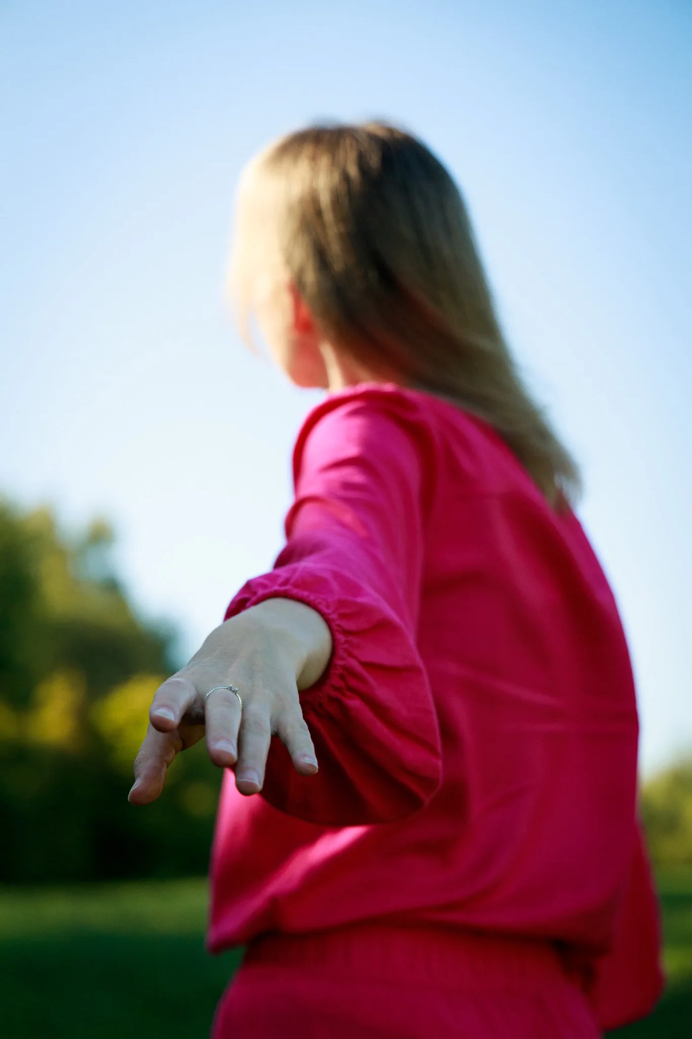 Gabriela v růžové košili natahuje ruku směrem k divákovi